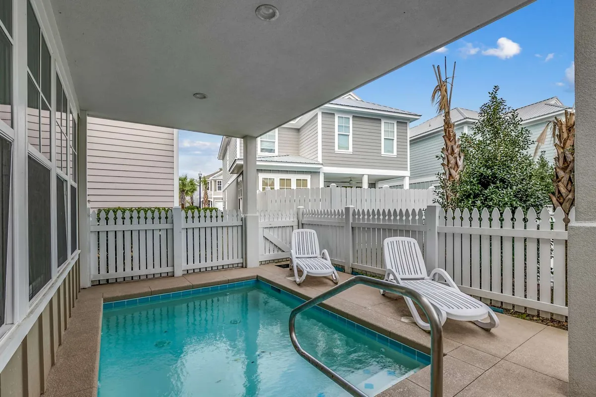 A tranquil pool scene with inviting lounge chairs lined up by a fenced swimming pool. The calm mood suggests a peaceful spot for sunset swims, quiet relaxation, or gathering with loved ones beside the water.