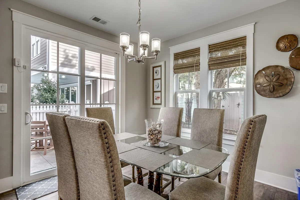 A warm, welcoming dining area with a large table set under a chandelier, flanked by windows that let in natural light. The décor is elegant yet comfortable, ideal for family dinners, celebrations, and group conversations.